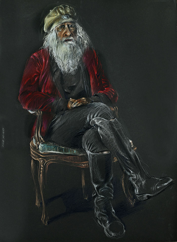 Seated portrait of a bearded man wearing riding boots.